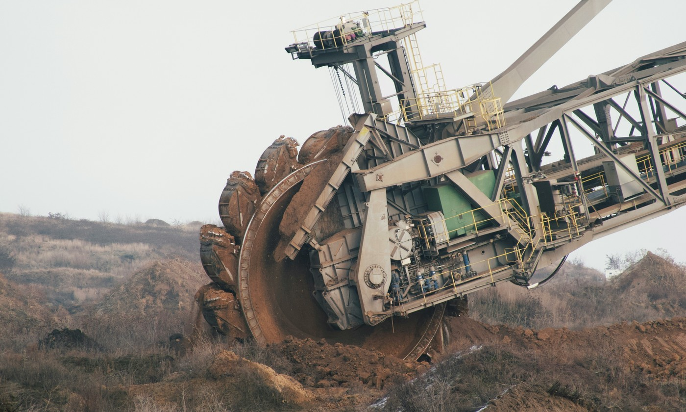 Giant bucket-wheel excavator digging earth in a mine quarry