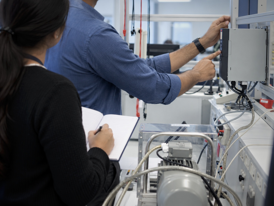 Engineers reviewing a Danfoss drive on a test bench during technical training